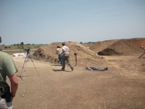 1996 Ford Bronco - A scene at a shooting range with people running and a dummy on the ground.