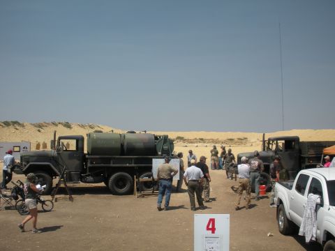 1996 Ford Bronco - A group of people gather around a military truck with water tanks in a desert-like environment.