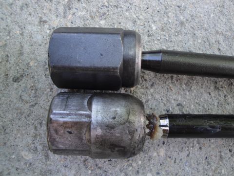 2003 Ford Taurus - Comparison of two tie rod ends, one appearing newer than the other, resting on a textured concrete background.