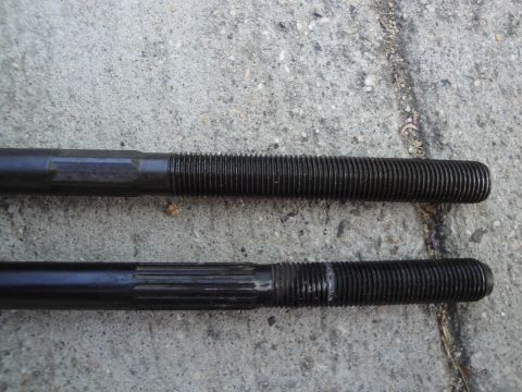 2003 Ford Taurus - Two black threaded rods are shown against a concrete surface. One rod has a smooth shaft, while the other features splines.