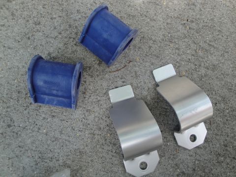 2003 Ford Taurus - Close-up view of automotive suspension parts, including blue rubber bushings and metal brackets, laid out on a concrete surface.