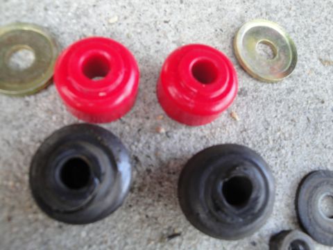 2003 Ford Taurus - A collection of red and black bushings, along with several washers, are laid out on a concrete surface.