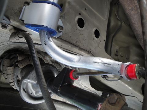 2003 Ford Taurus - Close-up view of aftermarket suspension components, including a silver control arm with blue and red bushings.