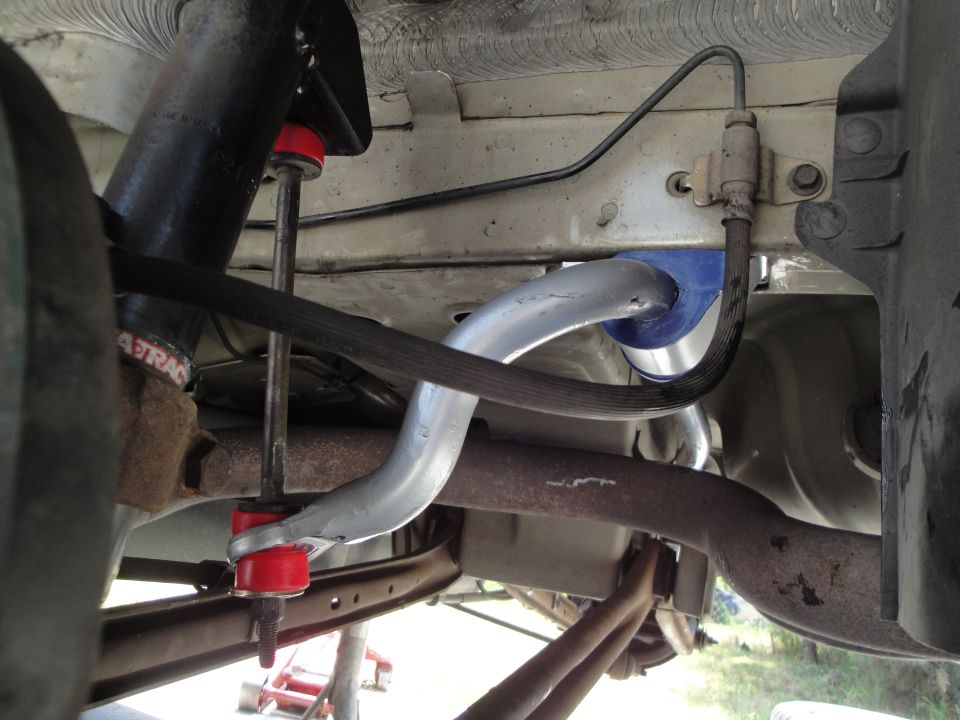 Close-up of a car's rear suspension with red bushings and a sway bar