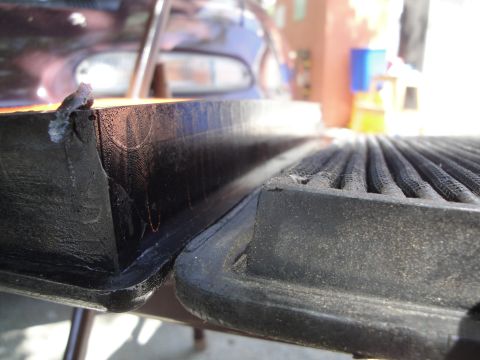 2003 Ford Taurus - The edge of a car's trunk lid shows wear and tear, with a ribbed surface visible.