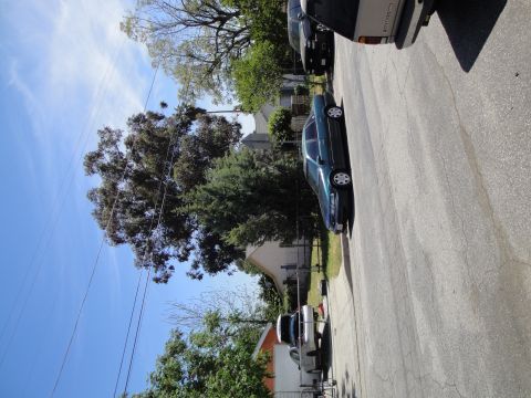 2003 Ford Taurus - A green sedan is parked on a residential street next to other vehicles.