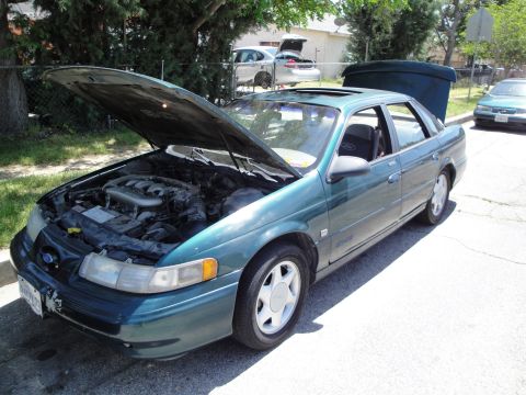 2003 Ford Taurus - Green 2003 Ford Taurus sedan with hood and trunk open, parked on a street.