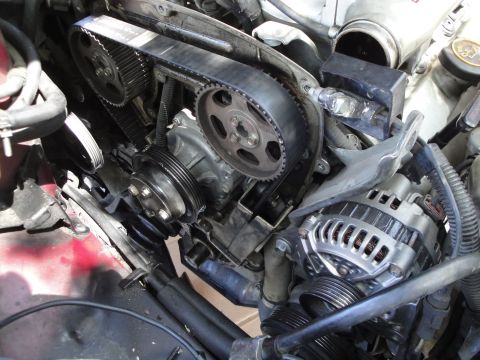 2003 Ford Taurus - Close-up view of the engine's timing belt, pulleys, water pump, and alternator.