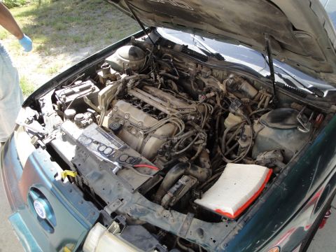 2003 Ford Taurus - The engine bay of a green 2003 Ford Taurus is shown with the hood open, revealing the engine and surrounding components.