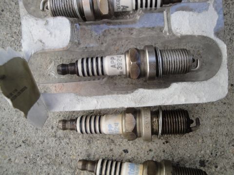2003 Ford Taurus - A set of four spark plugs, with part numbers visible on some, are packaged in a clear plastic holder.
