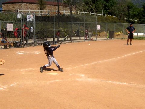 1996 Ford Bronco - A young baseball player takes a swing during a game on a sunny day.