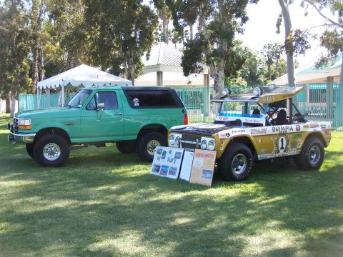 1990 Ford Bronco - Two Ford Broncos displayed on grass, one a stock 1990 model and the other a modified off-road racer.