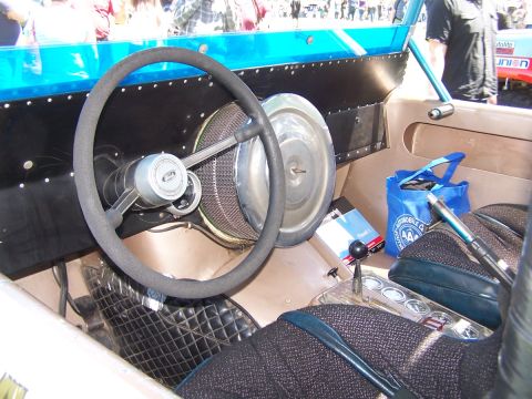 1990 Ford Bronco - Interior view of a custom car with a steering wheel, dashboard, and seats. A blue bag sits on the passenger side.