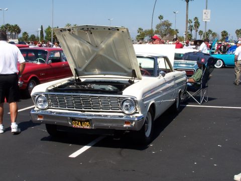 1990 Ford Bronco - White 1960 Ford Falcon on display at a car show, hood up, with other vehicles present.