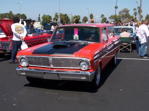 1990 Ford Bronco - A classic red station wagon is displayed at an outdoor car show with other vehicles and spectators.