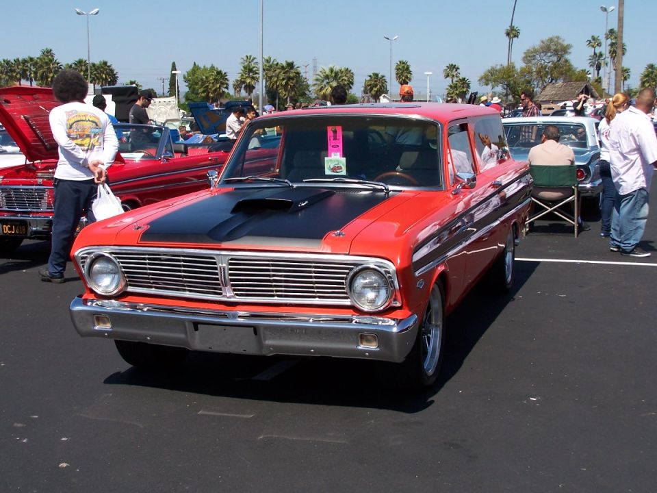 red station wagon with black hood scoop and racing stripes parked at a car show