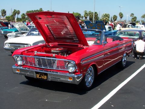 1990 Ford Bronco - A red 1963 Ford Falcon convertible is displayed with its hood open at a car show.