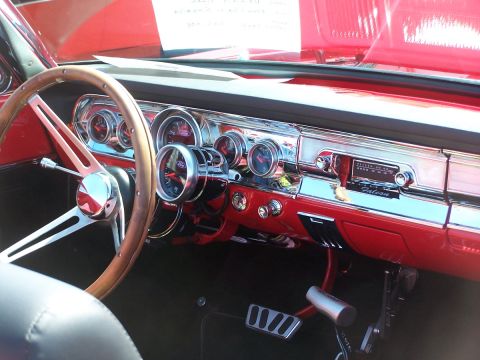 1990 Ford Bronco - The interior of a classic car features a red dashboard, custom gauges, and a vintage Falcon radio.