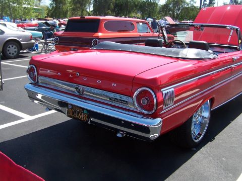 1990 Ford Bronco - A red convertible with chrome accents and 'FALCON' badging is parked at an outdoor event.