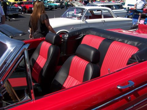 1990 Ford Bronco - Interior view of a red convertible with two-tone seats, parked at a car show with other vehicles present.