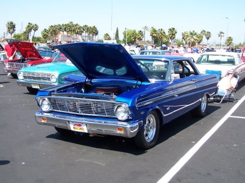1990 Ford Bronco - A blue classic car is parked with its hood open at an outdoor car show. Multiple vehicles are visible.