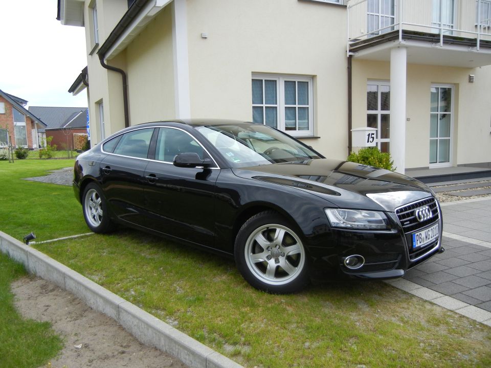 Black Audi coupe parked in front of a house. License plate is visible