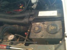 1988 Ford Bronco - Close-up view of an engine bay, showing hoses, a fluid reservoir, and a sticker on a component.