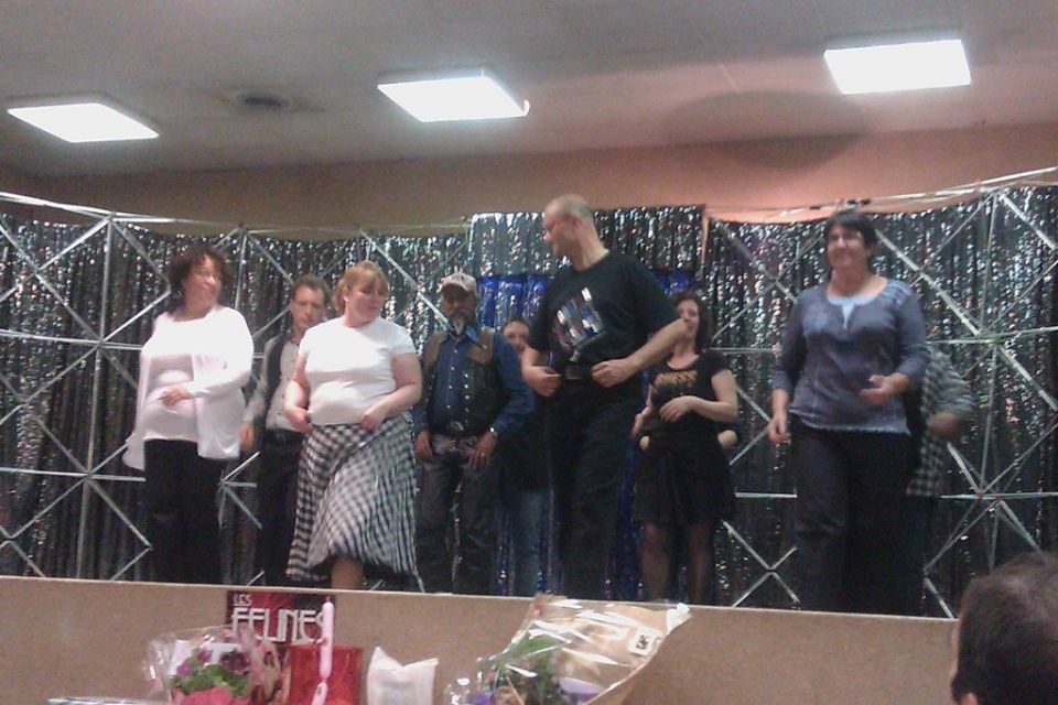 People on a stage with a sparkly backdrop and overhead lights