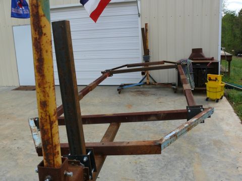 1976 Chevrolet Corvette - A rusty metal frame structure sits on a concrete pad in front of a garage.