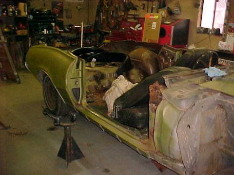 1969 Ford Torino - This car body, possibly undergoing restoration, is elevated on jack stands, revealing its stripped interior and side profile.