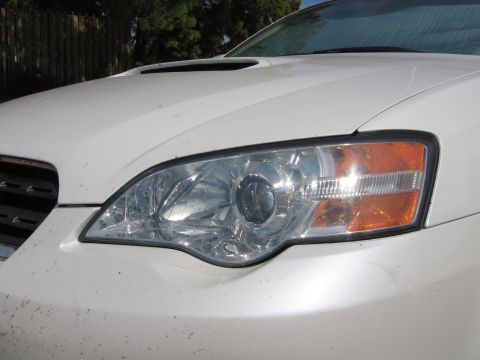 1993 Toyota 4Runner - Close-up of the front of a white Subaru Legacy, showing the headlight and grille detail.