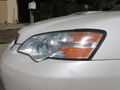 1993 Toyota 4Runner - Close-up of a white car's front end, focusing on the headlight assembly and bumper.