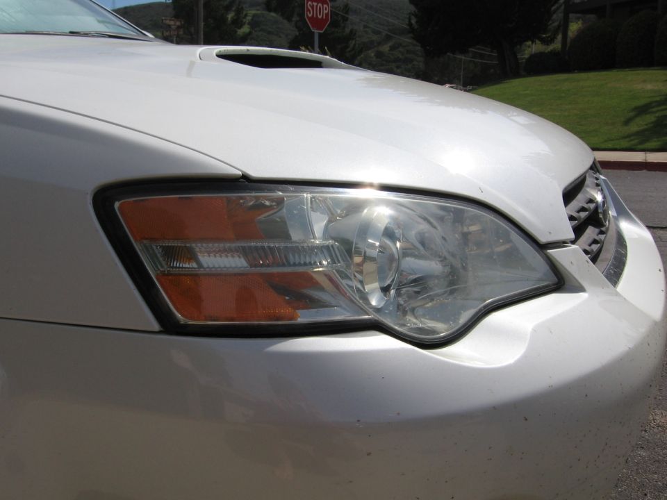White SUV front corner with headlight and hood scoop. Supermotors.net watermark visible