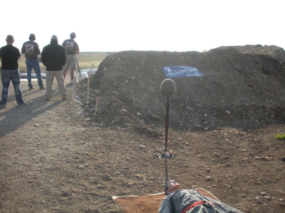 Memorial scene with helmet on pole, mannequin, and barbed wire
