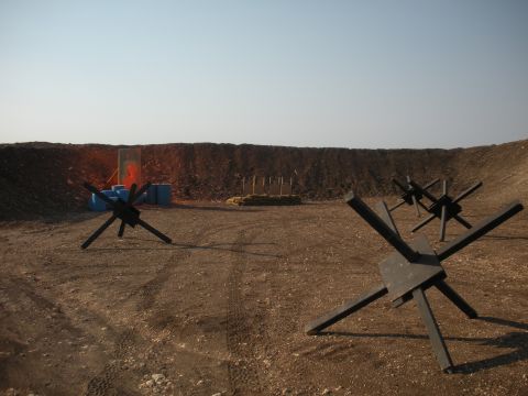 1996 Ford Bronco - Outdoor shooting range scene anti-tank obstacles and targets against a dirt berm.