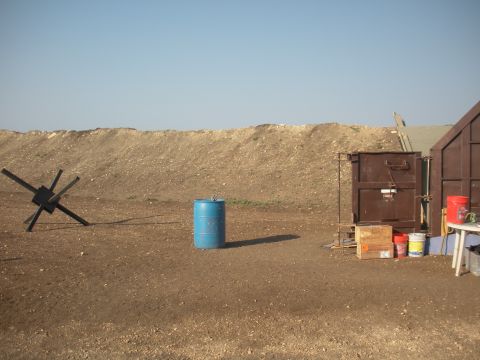 1996 Ford Bronco - This outdoor scene features a shooting range setup with various objects and a large dirt berm in the background.