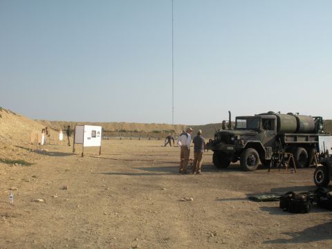 1996 Ford Bronco - A military truck with a water tank is parked at a shooting range with people and targets visible in the background.