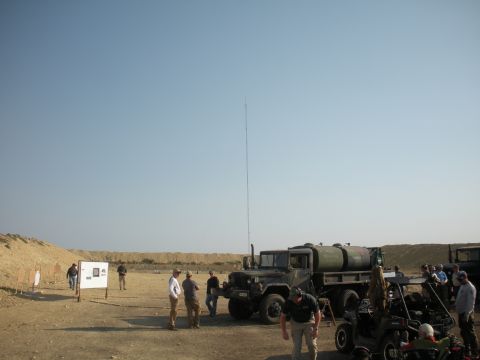 1996 Ford Bronco - Military truck and other vehicles at an outdoor shooting range under a clear blue sky.