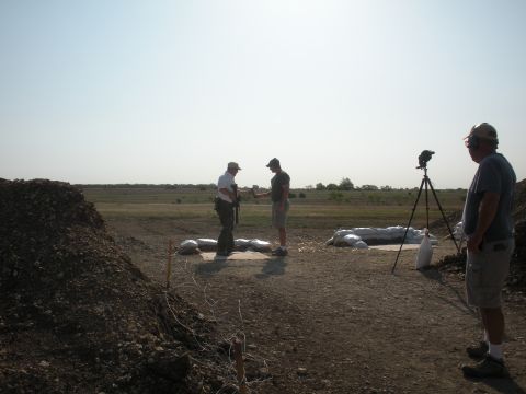 1996 Ford Bronco - A daytime scene at a shooting range shows three individuals, sandbags, and camera equipment under a clear sky.