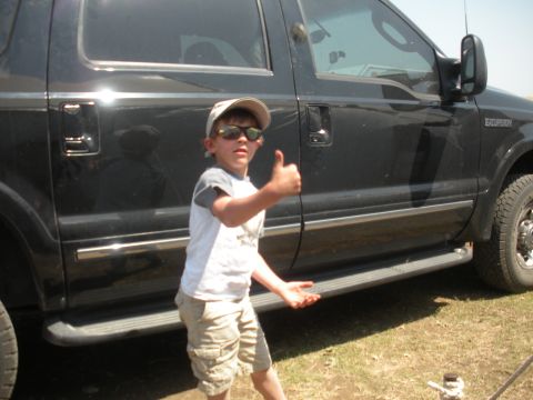 1996 Ford Bronco - A child poses next to a black SUV, giving a thumbs up.