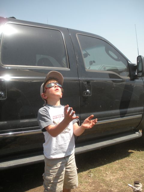 1996 Ford Bronco - A young boy looks up at the sky next to a large black SUV with running boards.