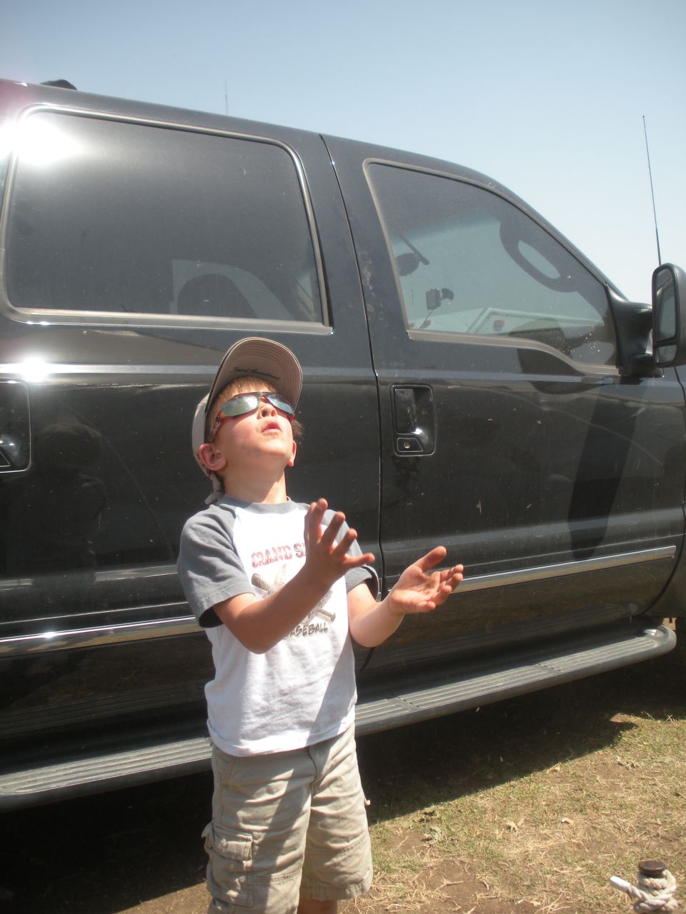 Side view of a black SUV with running boards, a boy looks up