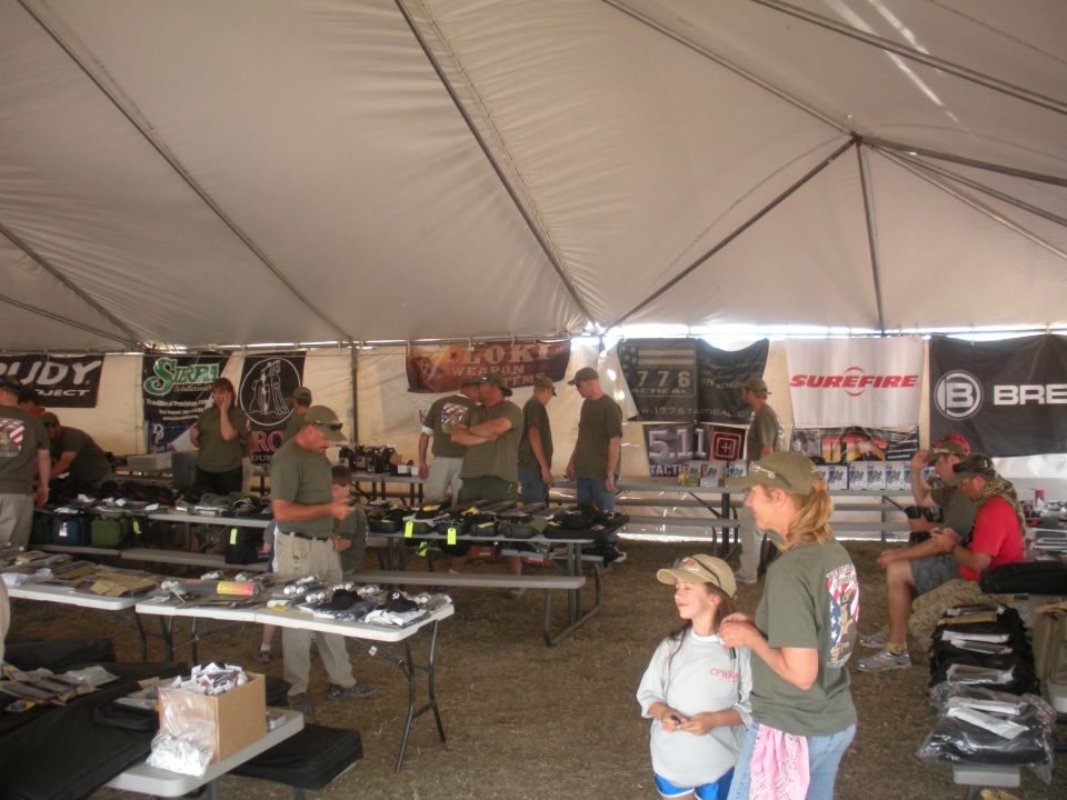 People browsing merchandise under a large tent with vendor banners