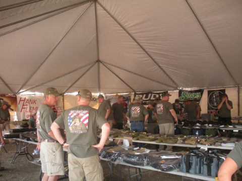 1996 Ford Bronco - An outdoor event with vendors and attendees under a large tent, displaying various goods on tables.