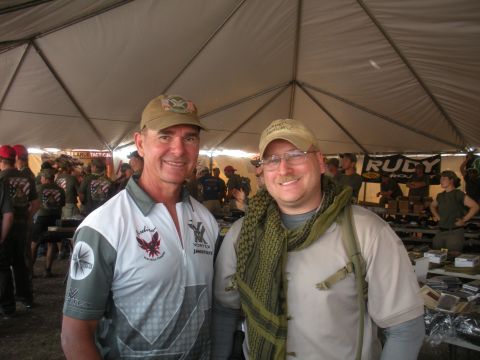 1996 Ford Bronco - Two men pose for a photo at an outdoor event, possibly a gun show or tactical expo, with merchandise and other attendees visible.