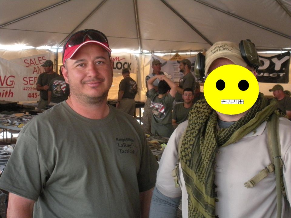 Two men stand in front of a tent display with tables of items behind them