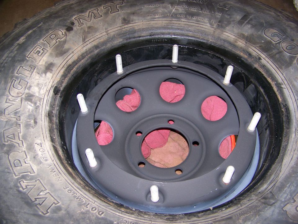 Close-up of a tire with a wheel and studs inside, red rags visible
