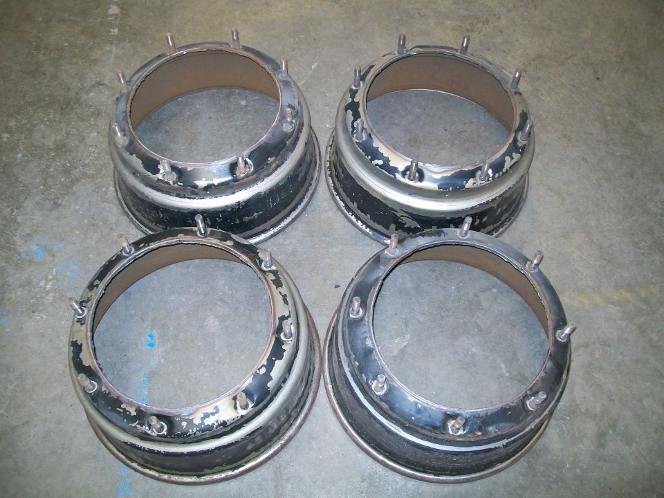 Four metal beadlock rings with studs, laid out on a concrete floor