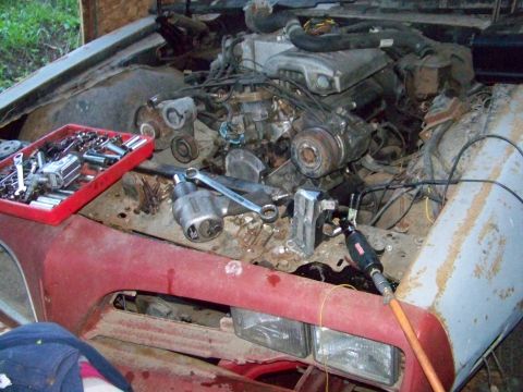 1978 Pontiac Trans Am - Tools are laid out in the engine bay of a vehicle undergoing repair.