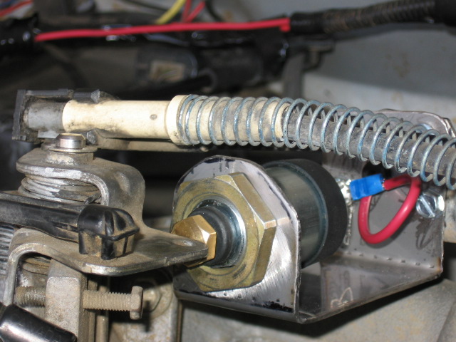 Bracket-mounted air fitting with brass nut, coiled braided line and red wiring in an engine bay